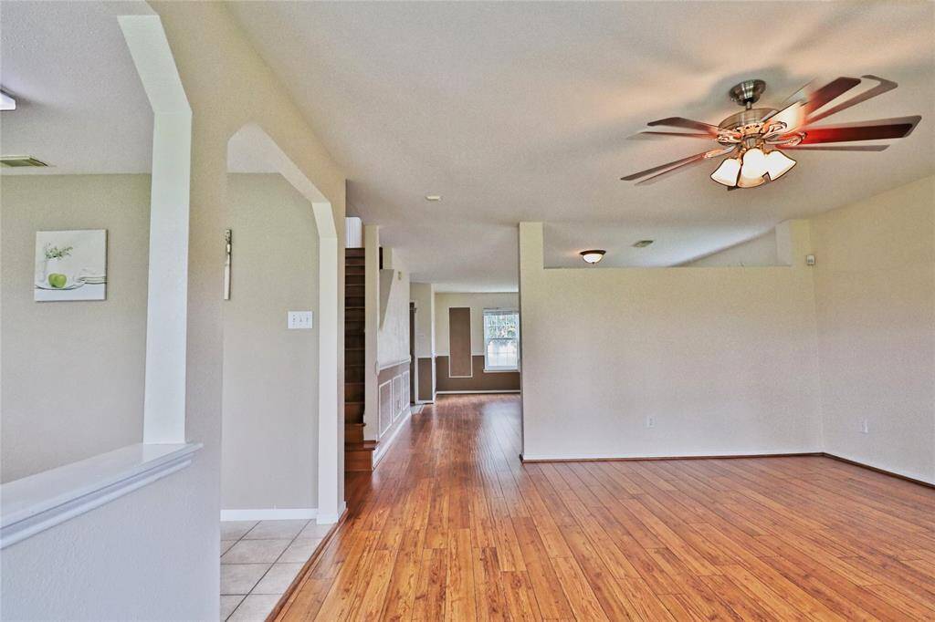 spacious, open-concept  family room with warm wooden flooring and complemented by a ceiling fan.