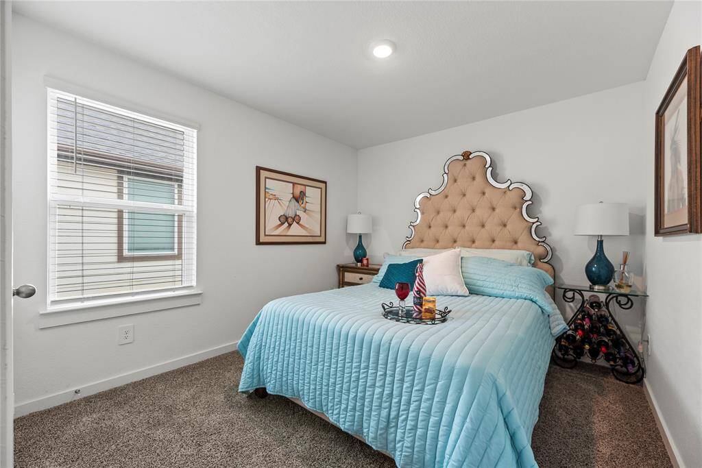 The extra bedroom features cozy carpet flooring and a generously sized window that lets in plenty of natural light. The recessed lighting in the ceiling provides a modern touch, offering well-distributed, soft illumination throughout the room. The light-colored walls enhance the feeling of openness, making the space feel bright and airy. It’s a versatile room that can easily adapt to a variety of uses, from a guest room to a home office, all while maintaining a welcoming and comfortable atmosphere.