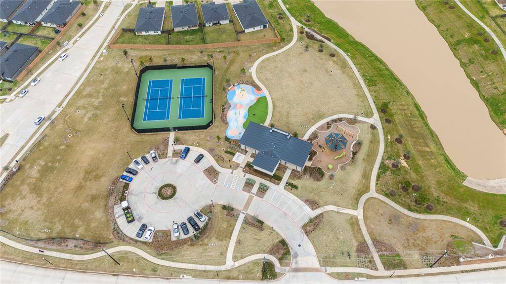 In addition to the pools, the neighborhood clubhouse offers a variety of other amenities to enjoy. There are two tennis courts, perfect for friendly matches or practice sessions. A fun splash pad provides a cool, interactive space for kids to enjoy water play during warm days. The playground offers a safe and exciting environment for children to climb, swing, and explore. For outdoor activities, a large grassy open space is available, ideal for picnics, sports, or simply relaxing in the sun.