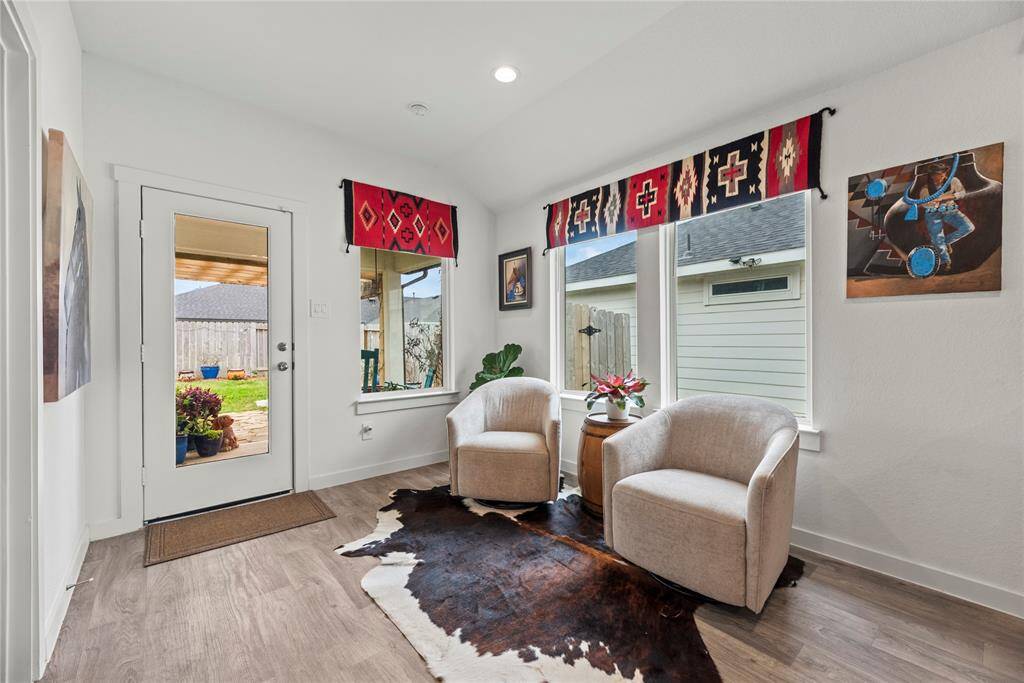 The breakfast area is bright and inviting, featuring a door with a large window that fills the space with natural light. In addition to the door, there are three other windows that offer views of the backyard, enhancing the open, airy feel of the room. The natural wood-colored LVP flooring flows throughout, adding warmth and a touch of elegance. The door conveniently leads to the backyard, making it easy to step outside and enjoy the outdoor space, perfect for meals or relaxing in the fresh air.
