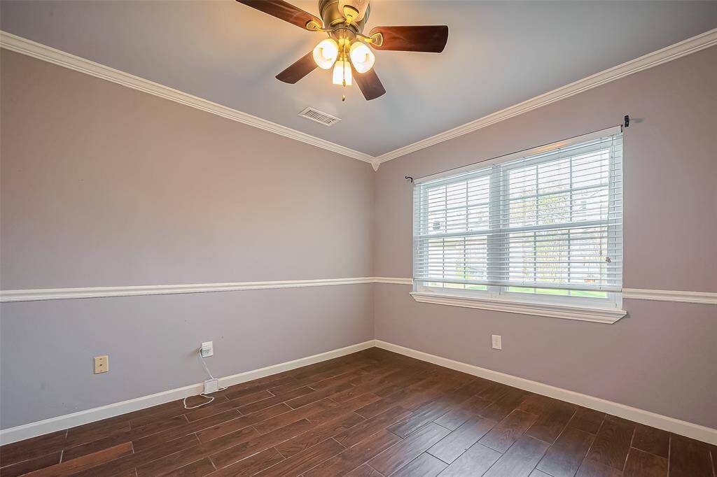 This room features a ceiling fan with lights, wood-style flooring, and large windows with blinds, offering ample natural light and a cozy atmosphere.