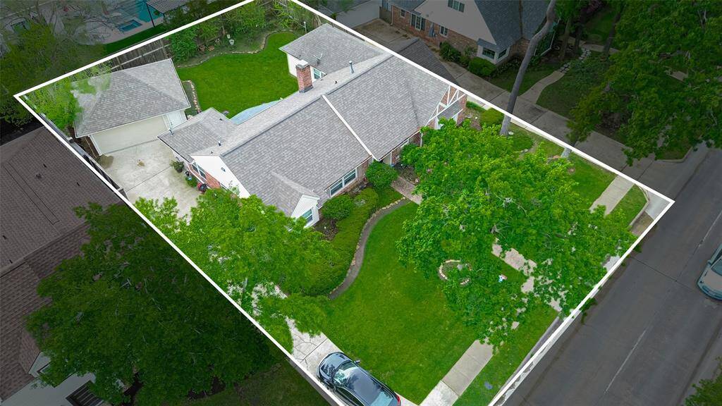 This aerial view showcases a charming single-story home with a well-maintained yard, mature trees, and a spacious driveway. The property features a detached garage and a private backyard, perfect for outdoor activities. Ideal for families seeking a peaceful neighborhood setting.