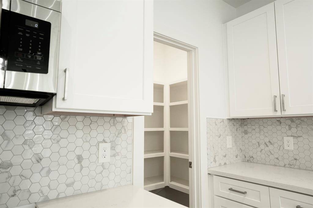 Large walk in pantry with new stainless steel appliances including pot filler.
