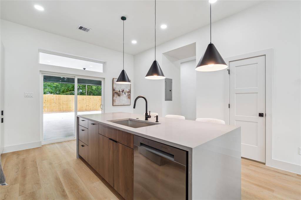 Earth-toned cabinetry pairs seamlessly with sleek countertops and modern lighting to create a balanced, high-design aesthetic that feels both grounded and refined.