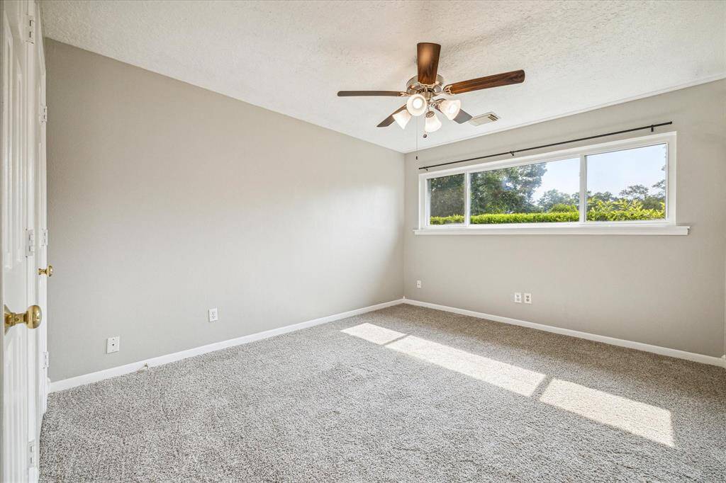 Secondary bedroom with natural light, ceiling fan, + TV mount [not pictured].