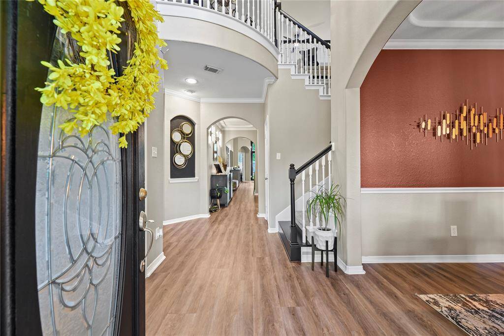 Grand and spectacular, the two-story foyer makes an impression on all your guests! Richly toned wood floors gleam in the presence of luminous natural light, while the above light fixture adds a touch of luxury.