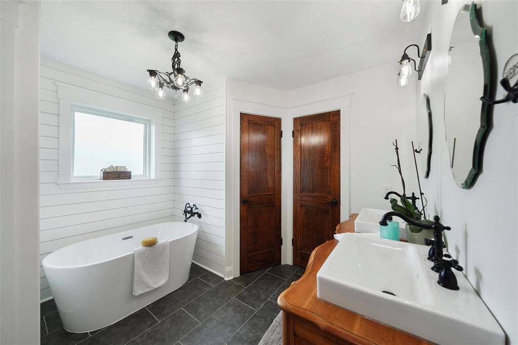 Freestanding tub with shiplap backdrop and soft lighting creates a spa-like atmosphere that’s both charming and relaxing.