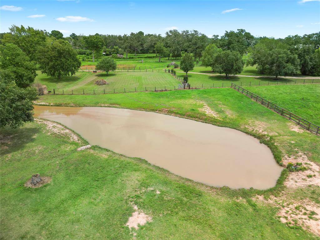 Overhead view showcasing the expansive pastures and serene pond. A great space for grazing or equestrian activities with ample room for additional landscaping or outdoor use.