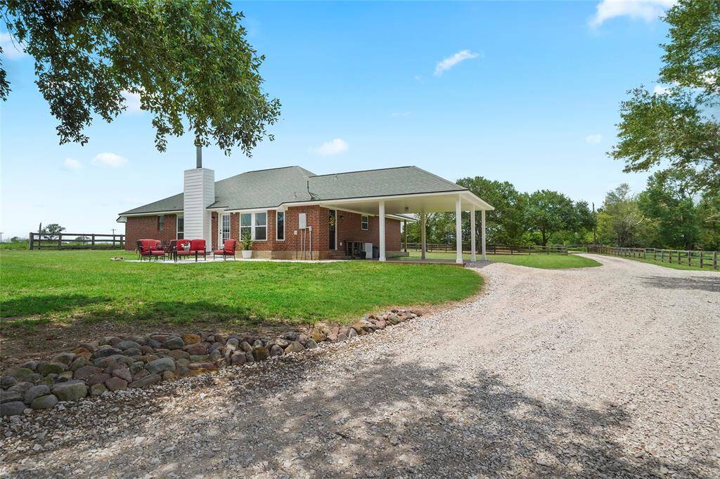 A charming country drive leads to the home, flanked by fenced pastures and mature trees—an idyllic setting from first glance.