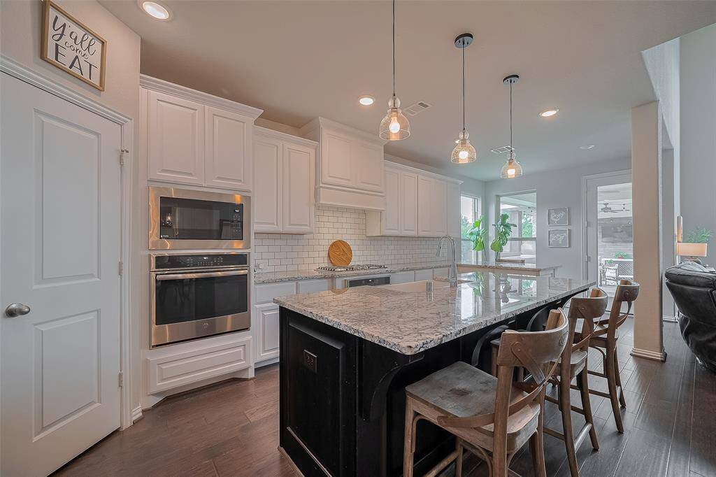 Now, let’s move to this fantastic kitchen—timeless and classic with its white subway tile backsplash, brand-new apron-front farmhouse sink, a contrasting granite island, and striking white upper and lower cabinets that create a bright, inviting space