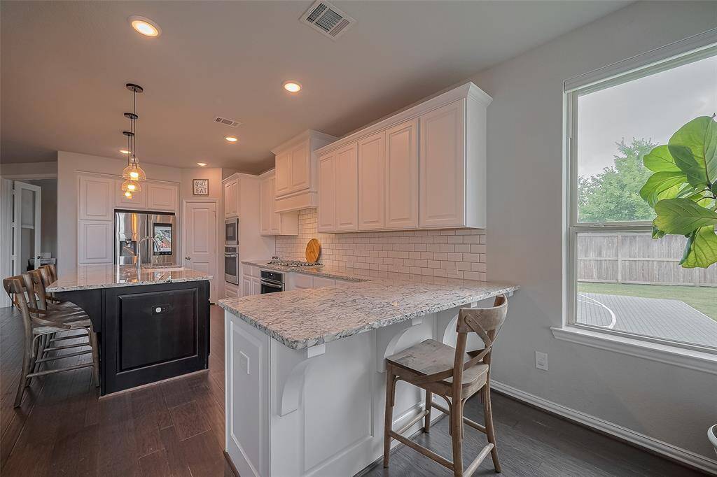 This alternate view of the kitchen highlights ample storage, featuring built-ins around the refrigerator and a walk-in pantry to the right. The cozy sitting area at the end is an ideal spot for homework or crafting while you prep dinner