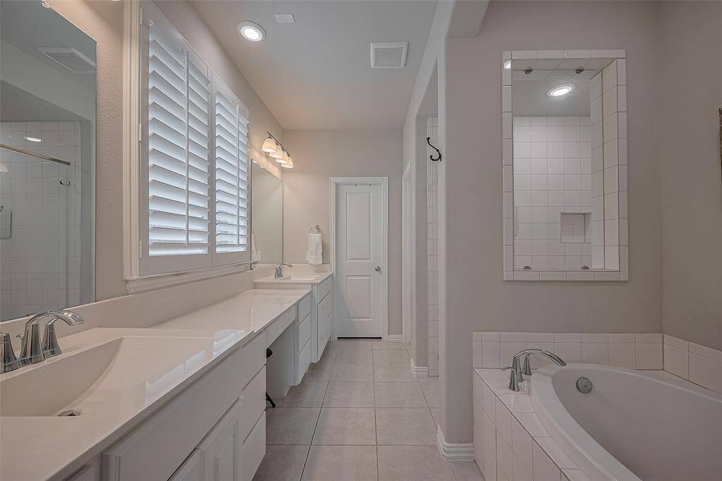 Inviting primary bath with soaking tub, stand alone shower, dual sinks, vanity and large primary closet for 2