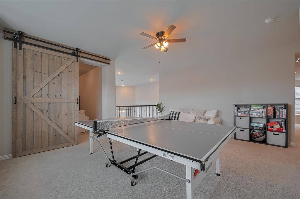 Adjacent to the game room is a dedicated media room, complete with custom built-in cabinetry and a stylish custom barn door for added privacy