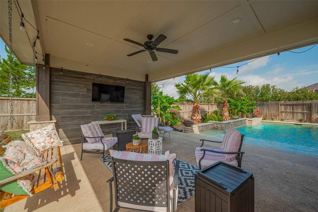 Enjoy the extended covered patio year-round, complete with recessed lighting, a ceiling fan, and a mounted TV—perfect for relaxing or entertaining in any season