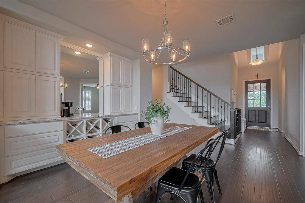 From this angle, you’ll appreciate the grand two-story foyer featuring a built-in drop zone, a beautifully crafted wooden staircase, and the true showstopper—a custom built-in hutch, perfect for effortless entertaining or serving meals with style