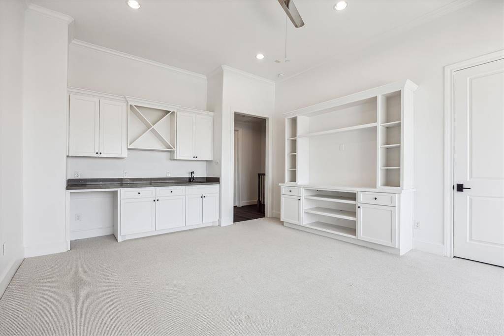 Built-in wet bar with sink and custom space for a beverage fridge with additional storage above and below wet bar, custom built-in entertainment cabinetry and additional closet for even more storage.