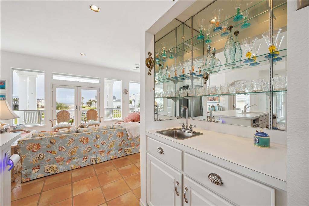 View of the fabulous wet bar with sink and beautiful mirrored display area for all your glassware and momentos. Easy access to the Kitchen and the Great Room.