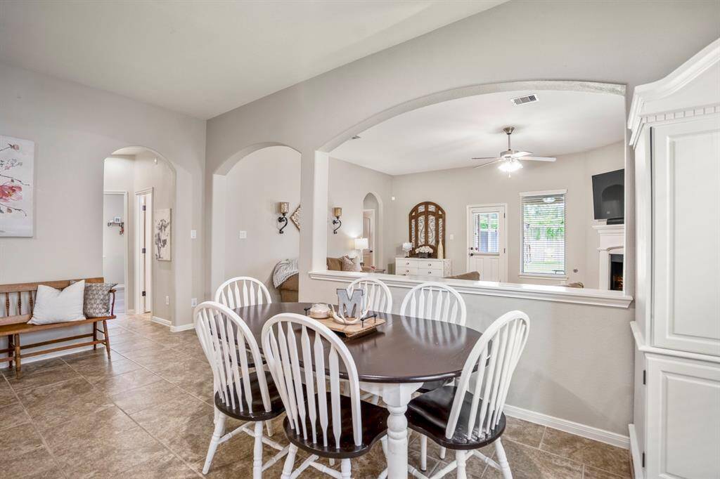 Just steps from the kitchen, the dining area welcomes plenty of natural light. To the left, an arched doorway opens to a hallway leading to two bedrooms, creating a thoughtful and connected floor plan.