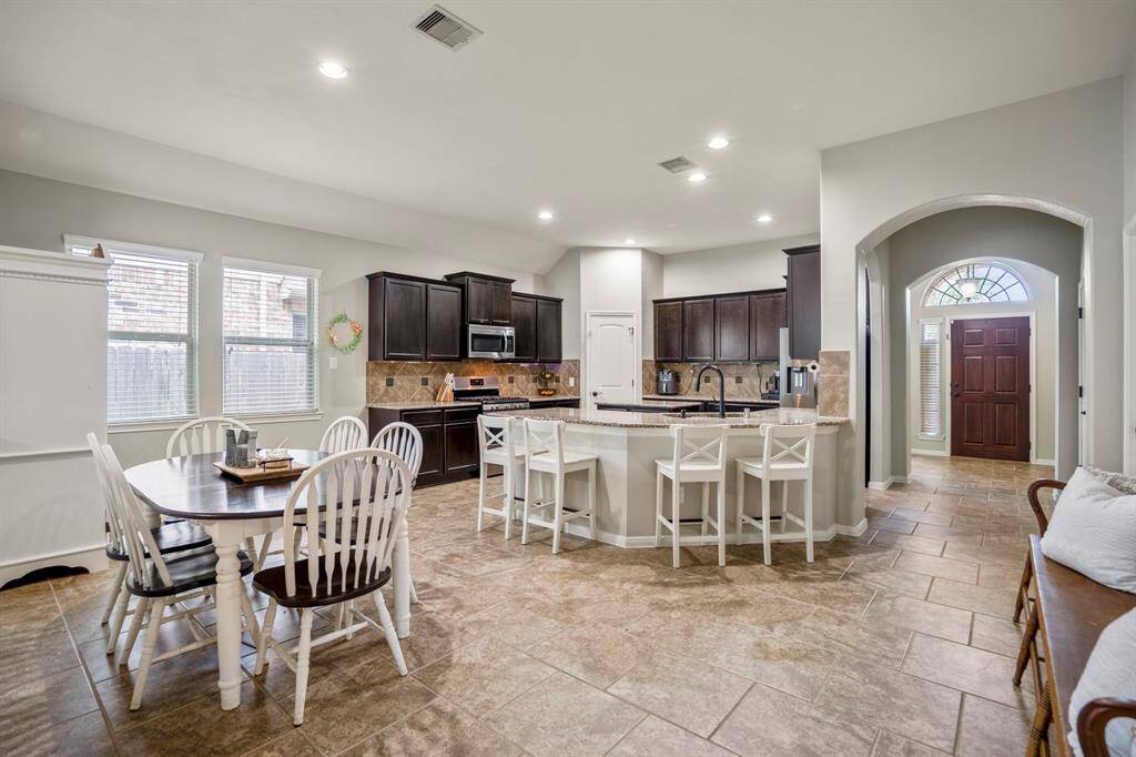 This view showcases how seamlessly the kitchen, dining, and entryway connect—creating a space that’s as functional as it is welcoming. Picture mornings at the breakfast bar, natural light pouring in through the dining windows, and everyday moments unfolding effortlessly in a layout designed for easy living.