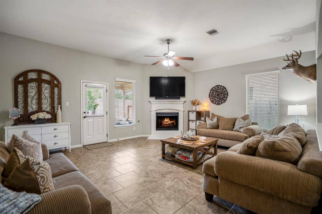 Natural light pours through the windows, gleaming off the tile floors as you step into the living room. A corner fireplace anchors the space with warmth and character.