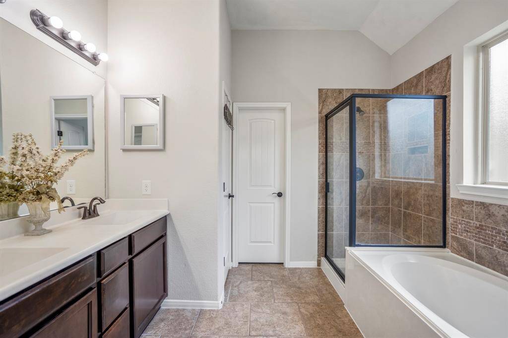 Step inside the primary bathroom, where dual sinks offer plenty of space to start and end your day. To the right, a separate tile shower and soaking tub invite relaxation, while straight ahead, the walk-in closet awaits. Between the sinks and closet, a private water closet adds convenience and privacy to this thoughtful space.