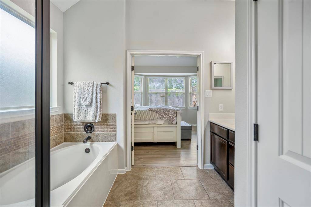 From the walk-in closet, take in the calming view back across the bathroom and through the open double doors to the inviting primary bedroom — a seamless flow that ties this private retreat together beautifully.