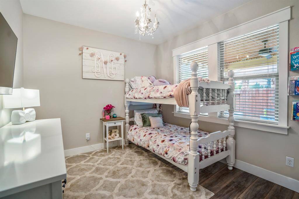 Just steps from the primary suite, this cozy bedroom features charming cased windows that overlook the back porch. With vinyl plank floors underfoot and a delicate chandelier overhead, it’s a bright and inviting space perfect for rest or creativity.