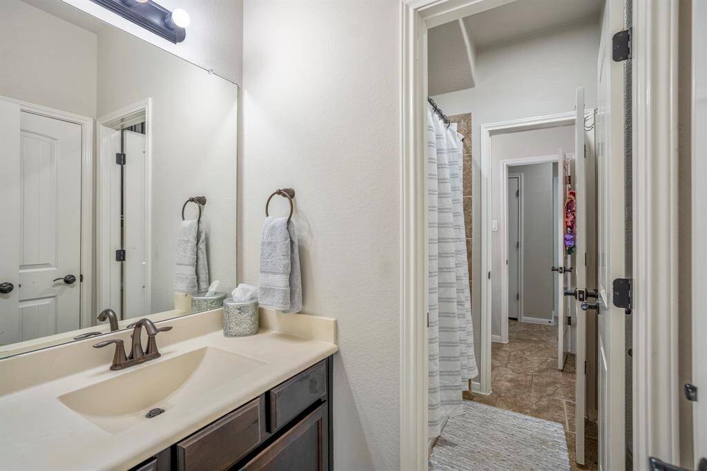 Here’s the first glimpse into the smartly designed Jack-and-Jill bathroom, positioned between two hallways. To the left, the first vanity offers plenty of space, and reflected in the mirror, you’ll spot a handy linen closet. Straight ahead, the tub and shower sit just inside the doorway, with the toilet tucked discreetly out of view. Beyond, the second vanity leads to the other hallway — a layout made for smooth, shared routines.