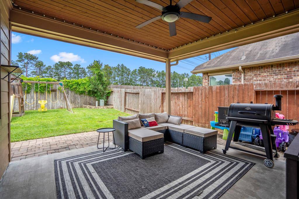 Step outside to the inviting covered patio, where a striking wood-plank ceiling adds warmth and character. The paver stone patio extends the space beautifully, flowing into a lush, green lawn — perfect for relaxing or entertaining outdoors.