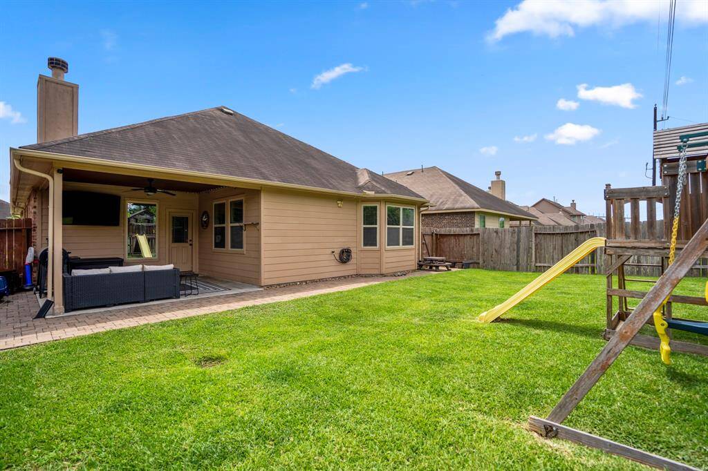 From near the back fence, take in another view of the spacious yard and paver stone patio extension. Thoughtful details like gutters and a French drain help keep the space dry and well cared for, so you can simply enjoy your outdoor retreat.