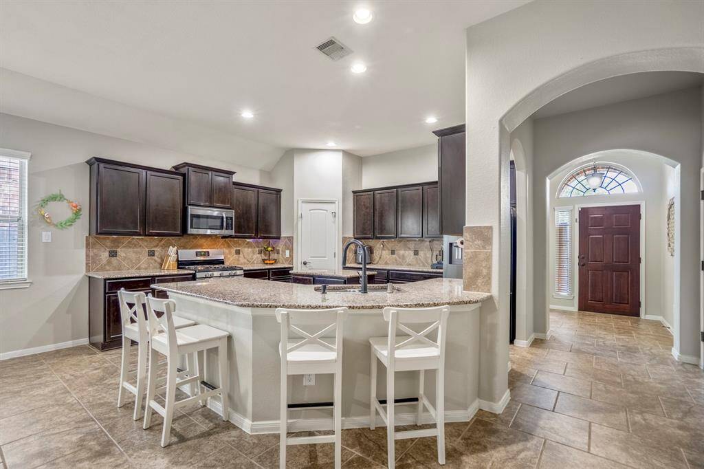 As you move deeper into your future home, glance back through graceful arches toward the front door, while the spacious kitchen welcomes you on the left—highlighting the open flow that makes daily life easy and connected.