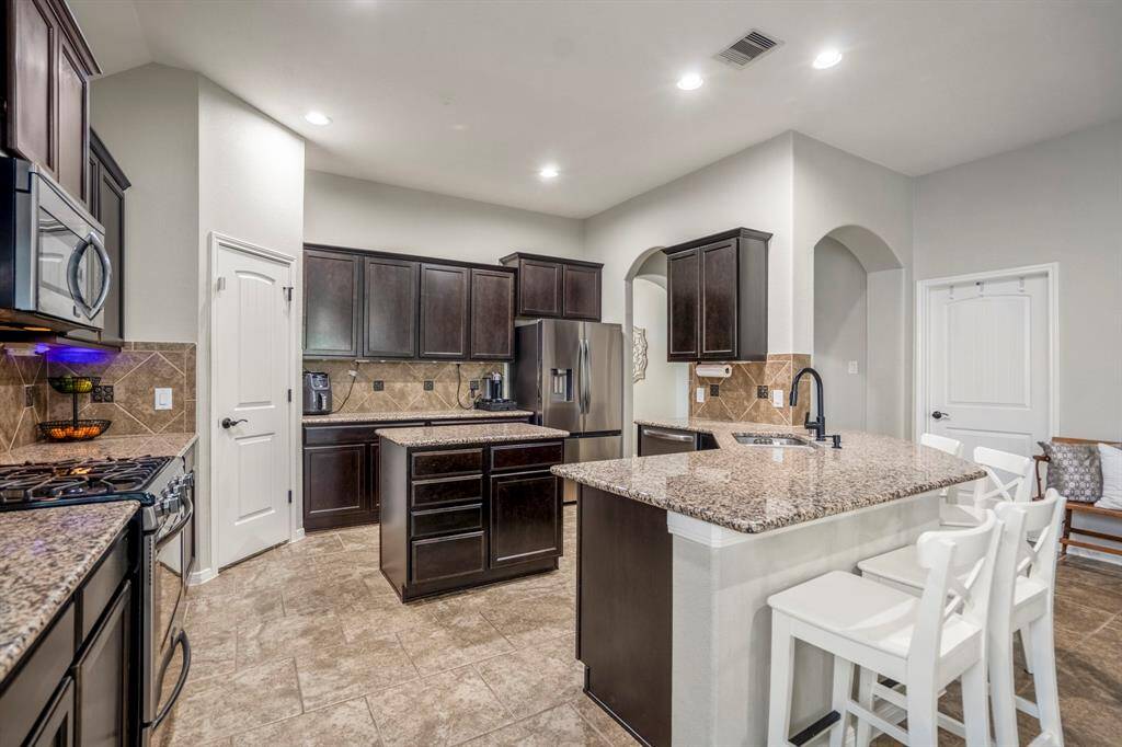 Imagine cooking in your kitchen with abundant counter and cabinet space. The island sits between the sink and pantry, while the eating bar by the sink makes a great spot for casual meals or conversation. Just beyond, the laundry room door sits next to the arched doorway leading back to your foyer.