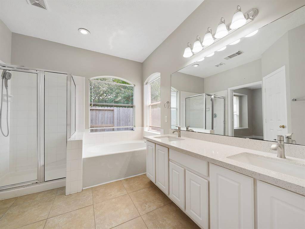 The primary ensuite bathroom offers exceptional functionality and comfort. Featuring an extended vanity with double sinks and generous storage, getting ready each morning is a breeze. Enjoy a long soak in the tub, or opt for a quick rinse in the separate shower. This well-designed space caters to all your needs.