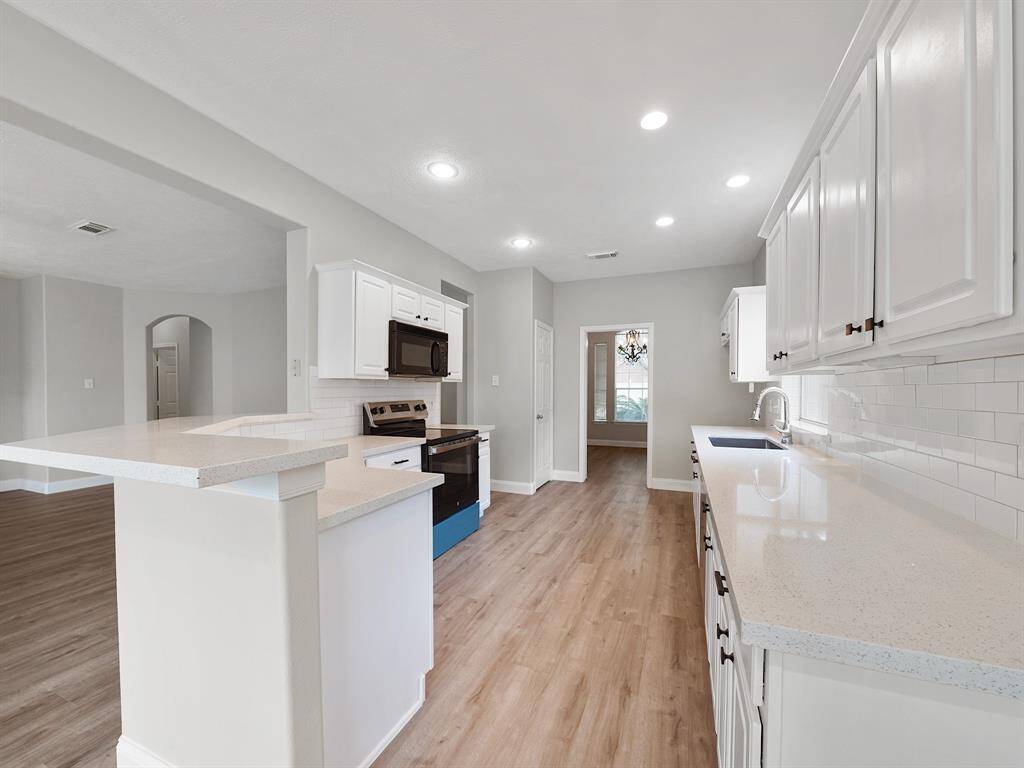A seamless passthrough entryway leads to the light and bright kitchen, complete with quartz countertops, a stylish subway tile backsplash, and a spacious pantry.