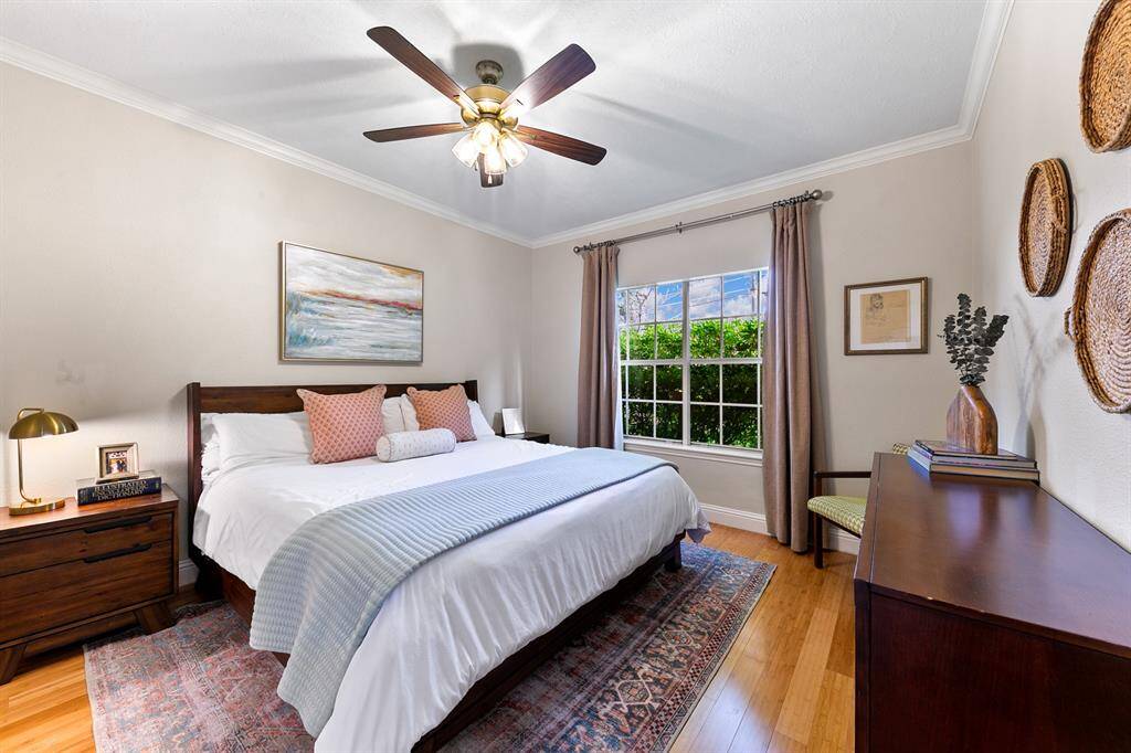 Across the great room from the kitchen and breakfast room,, the expansive first-floor primary suite features a private view of the lush backyard.  Two generously sized walk-in closets, elegant bamboo flooring, and sophisticated crown molding create luxurious retreat for the homeowners.