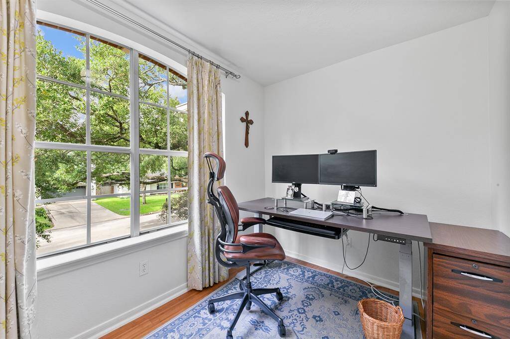 Adjacent to the game room, this cozy flex space, currently used as a home office, can be easily converted into an art room, library, nursery, or fifth bedroom for guests.  An elegant arched picture window frames treetop views, filling the space with natural light and creating a serene backdrop for work or relaxation.
