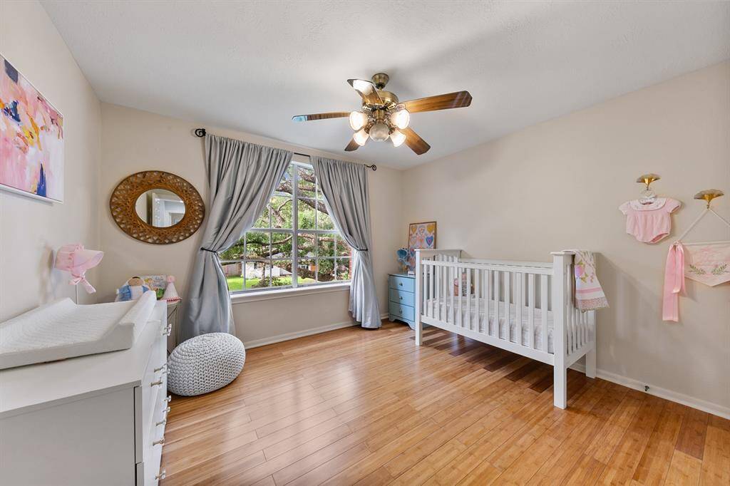 Positioned at the far end of the second floor, two well-appointed secondary bedrooms and a spacious guest bathroom ensure comfortable accommodations for the entire family. This bedroom is currently used as nursery and features picturesque views of the gorgeous live oak in the front yard and engineered bamboo flooring.