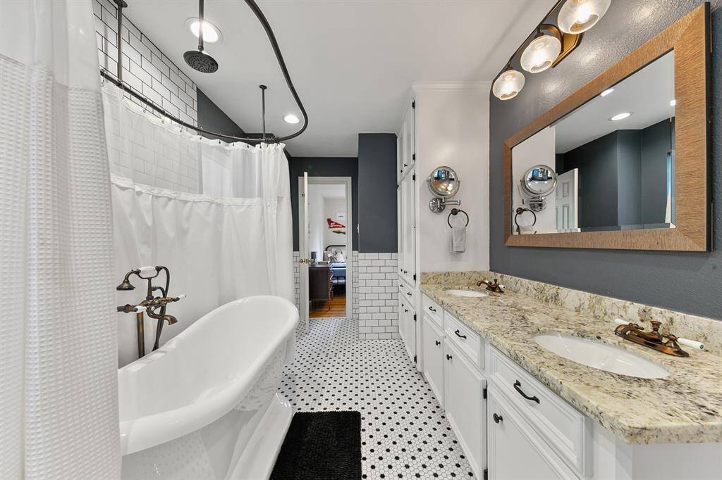 The large, well-designed secondary bathroom is perfect for busy mornings and relaxing evenings even with several family members vying for space at the same time.  It features double undermount sinks with gleaming granite countertops, stylish bronze fixtures, plenty of storage, and a beautiful freestanding slipper tub with a rain shower and European wand, offering stylish comfort and convenience for whole family.