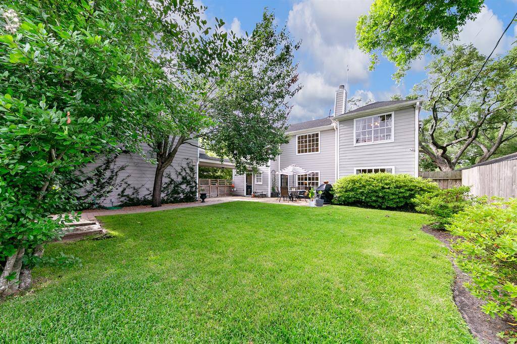 The oversized backyard offers a beautifully maintained lawn framed by established azaleas and fragrant climbing star jasmine.  A deep flagstone patio with a direct-line gas grill (included in the sale) provides ample space for outdoor dining and gatherings, while a garden-style paver walkway curves gracefully along the side of the garage, guiding you to the garage apartment and to the built-in sandbox beyond.