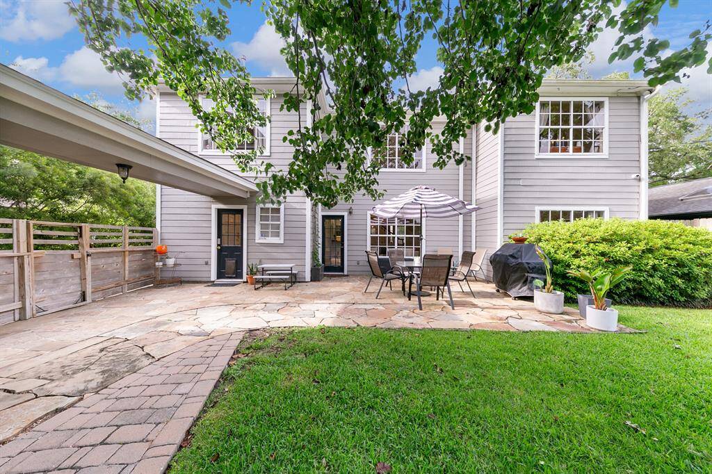 The covered walkway connecting the back door to the garage and studio apartment is both practical and welcoming, with a clean, stylish privacy fence running along the driveway for added comfort and privacy