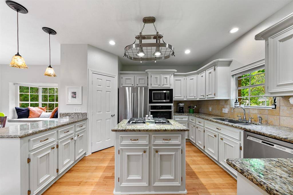 The gourmet kitchen is luxuriously designed with double undermount sinks, elegant neutral granite countertops complemented by a travertine backsplash, and a spacious granite island featuring a gas range and griddle. High-end stainless-steel appliances complete the heart of the home, offering both style and functionality for the daily culinary chef.