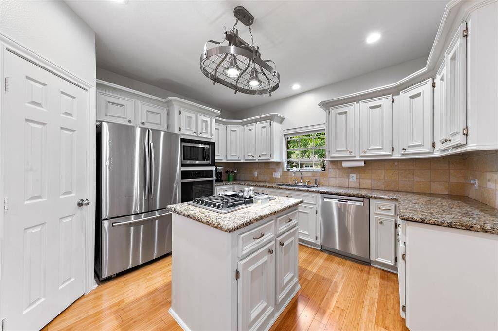 The gourmet island kitchen is designed to offer every convenience. Newly painted cabinets in soothing neutral tones create a serene backdrop, making daily cooking effortless with ample cabinet storage and expansive prep space illuminated by under-cabinet lighting.  The unique pot rack above the island increases storage space without sacrificing light.