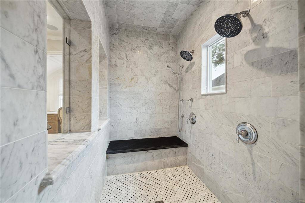 Oversized primary bath shower with dual shower heads, seat and luxurious fixtures and finishes.