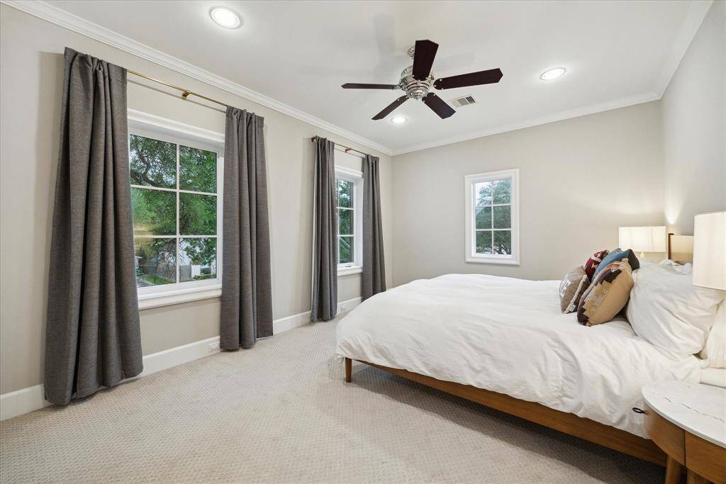 Secondary bedroom with designer draperies, crown molding and ceiling fan.