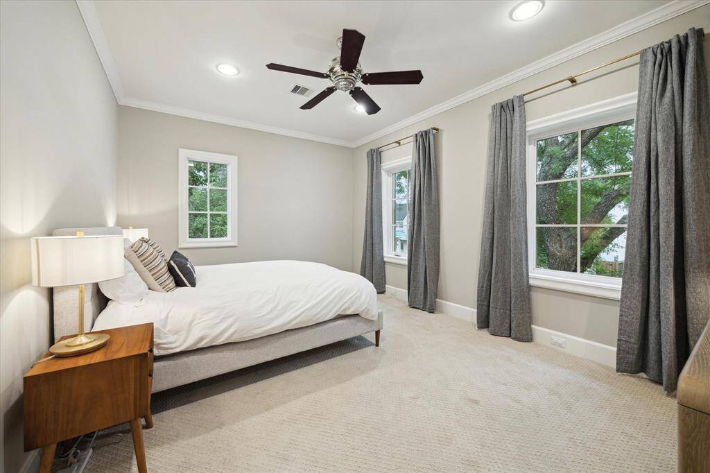 Secondary bedroom with designer draperies, crown molding and ceiling fan.