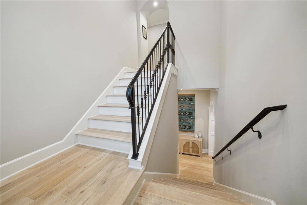 The staircase seamlessly combines modern elegance with traditional craftsmanship, featuring a striking wrought iron handrail and balusters.