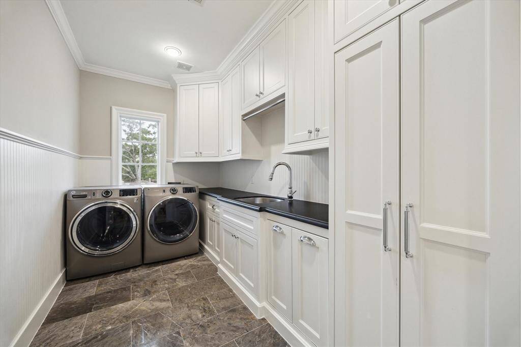 Upstairs laundry room with abundance of cabinetry, utility sink and bead-board panelling.