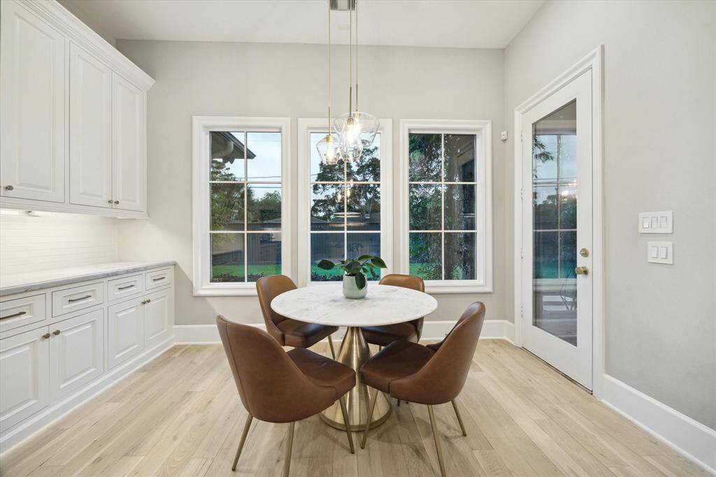 Charming breakfast room features light wood flooring, wall of buffet-style counter and cabinets, complete with under-cabinet lighting, adds both style and convenience.