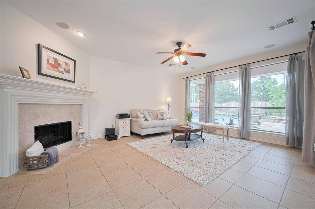 Spacious living room features large windows for natural light, a cozy fireplace, and beautiful back yard view.