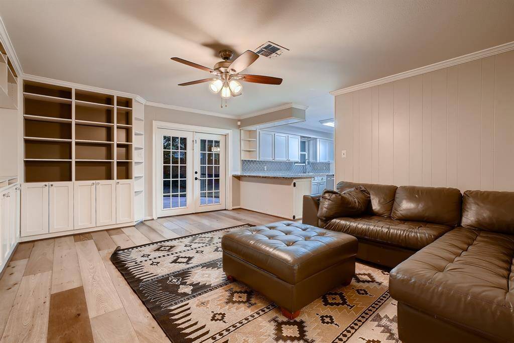 Large den features built-ins, a dedicated space for your entertainment center, and French doors leading to the back yard.